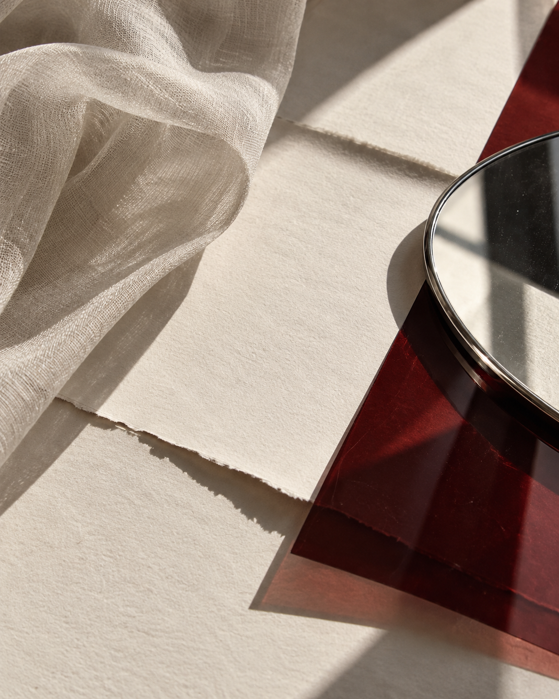 Sunlit bone paper, sheer fabric, a chrome mirror and deep oxblood acetate.